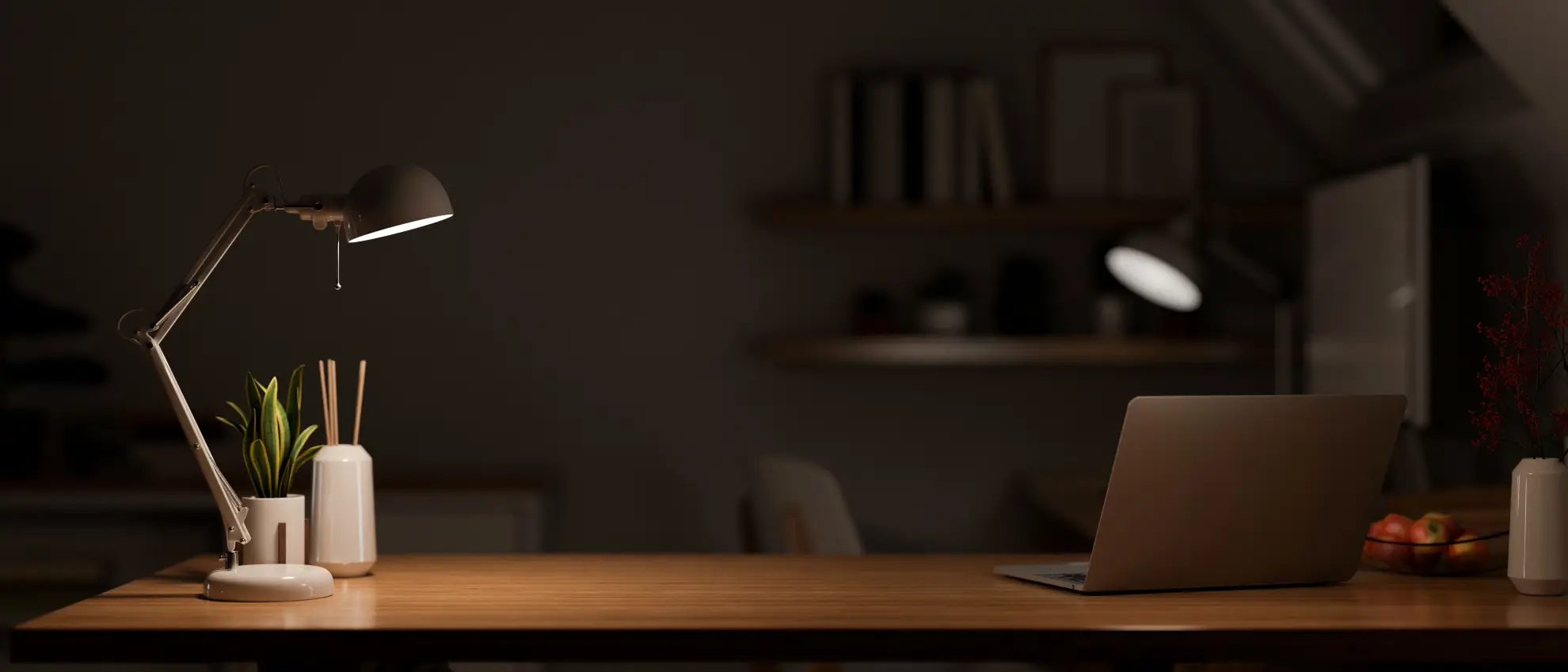 A laptop on a desk at night, lit by a single lamp